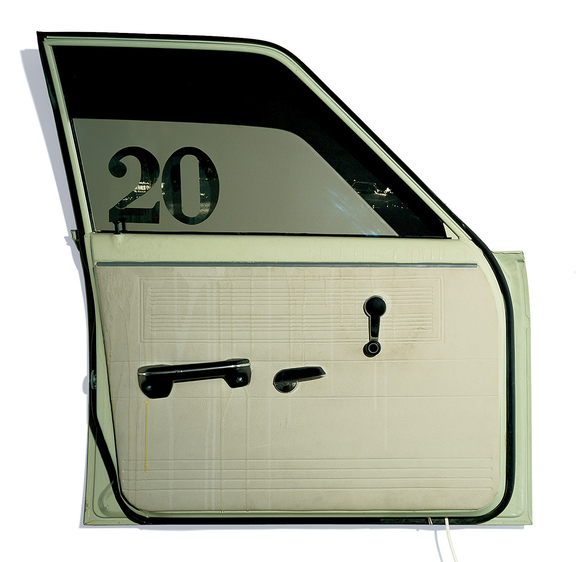 The image depicts the installation Sawdy by Ed Kienholz, which is constructed from a green car door. The car door window is partially lowered and has the number 20 on it.